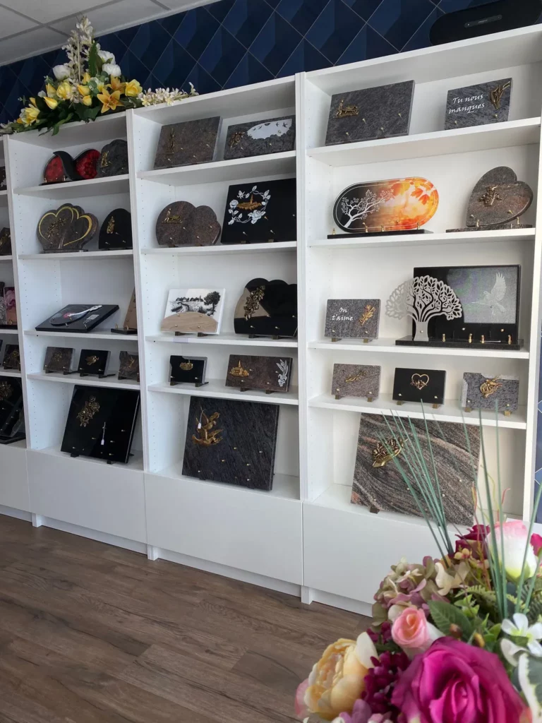 Plaques funéraires personnalisées exposées sur des étagères blanches.