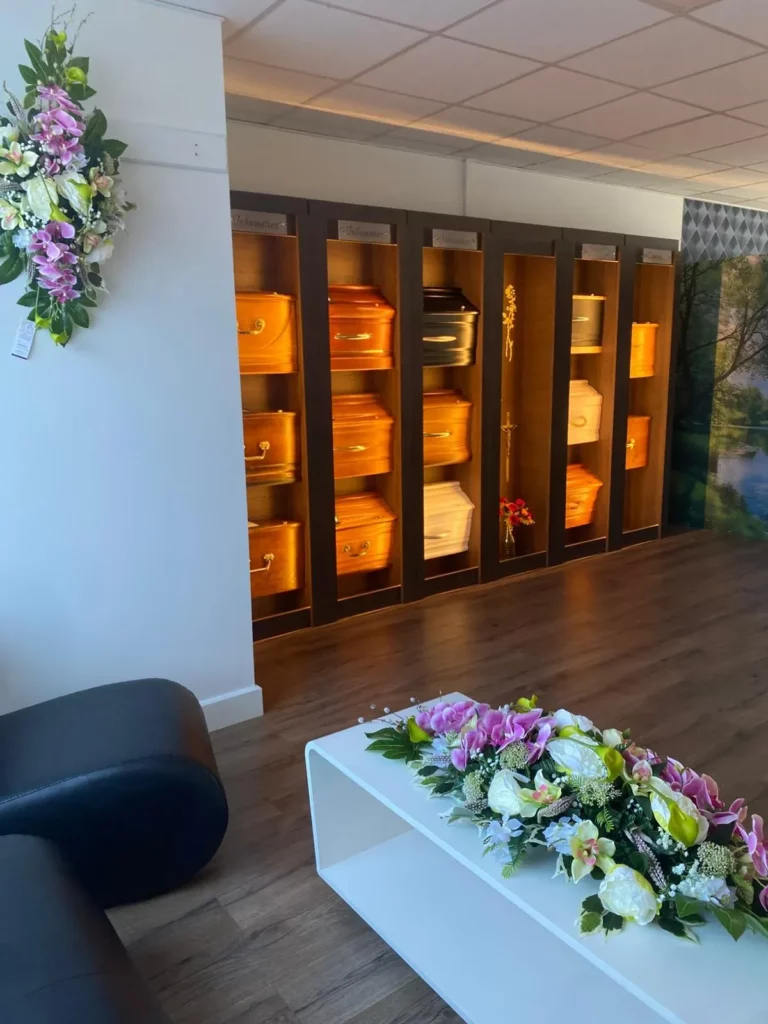 Exposition de cercueils et compositions florales dans un magasin funéraire.