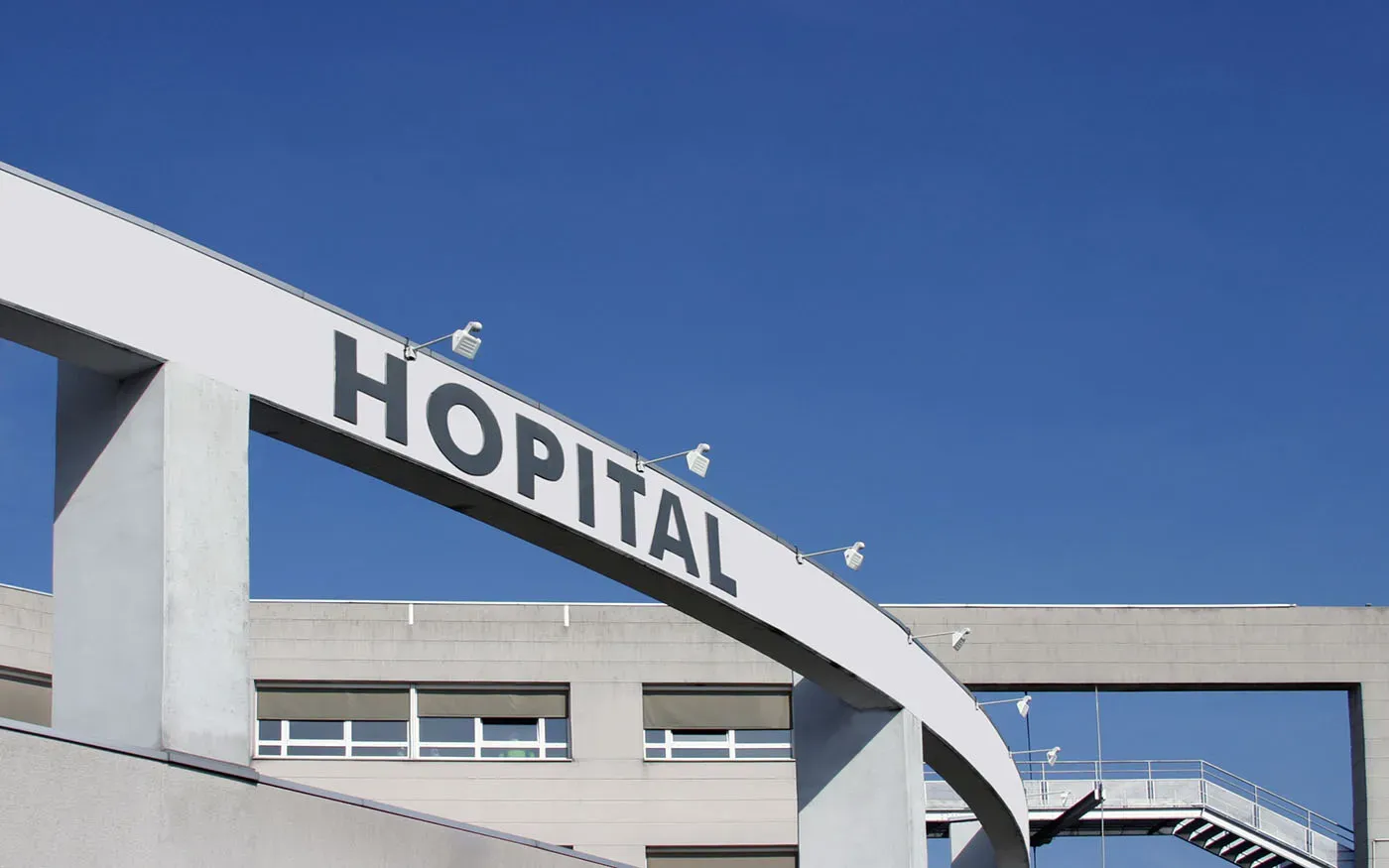 Panneau d'entrée d'un hôpital public sous un ciel bleu ensoleillé.